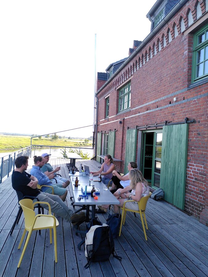 Genoss:innen der machBar Zapferei eG bei einem Arbeitstreffen auf der Terrasse des Kranhauses.